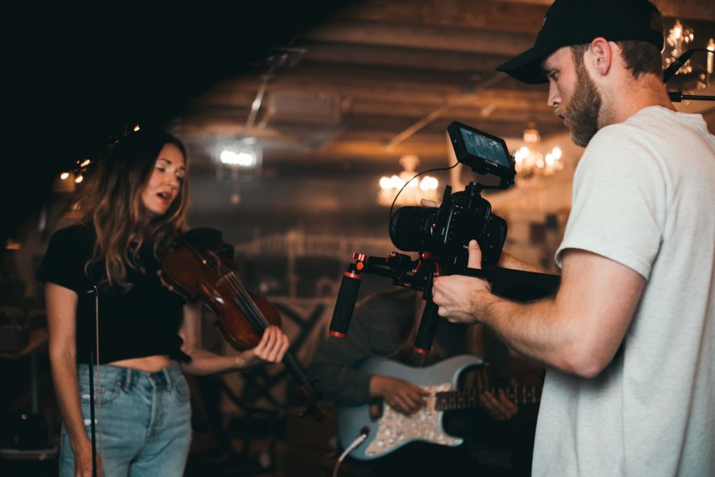 muž natáčející koncert na fotoaparát se stabilizátorem