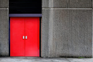 Closed red metal door in a modern concrete building
