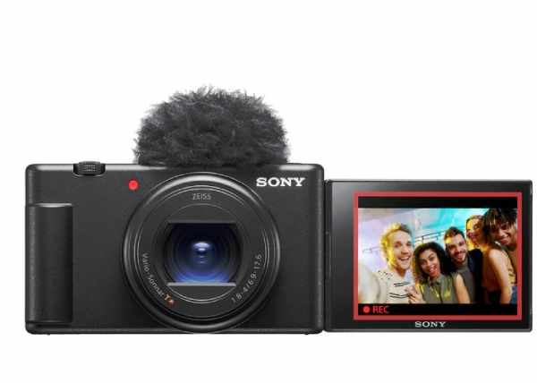 Kompaktní černá kamera Sony se směrovým mikrofonem a otočným displejem zobrazujícím skupinové fotografie.