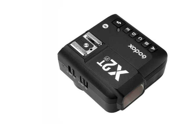 Bezdrátový vysílač Godox X2T na bílém pozadí, černý design s ovládacími tlačítky a sáňkami pro blesk