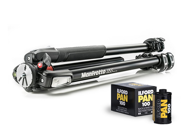 Složený černý stativ Manfrotto 055 vedle dvou černobílých filmů Ilford PAN 100 Složený černý stativ Manfrotto 055 vedle dvou černobílých filmů Ilford PAN 100