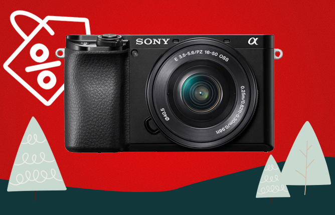 Sony fotoaparát s objektivem na červeném pozadí, ozdoben vánočními motivy a symbol slevy Sony fotoaparát s objektivem na červeném pozadí, ozdoben vánočními motivy a symbol slevy
